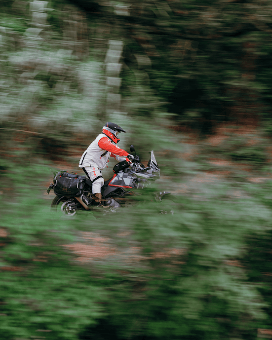 Motard roulant dans la nature équipé de matériel Fuel