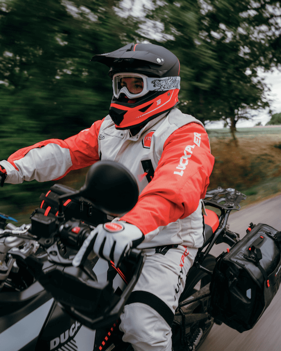 Motard roulant dans la nature équipé de matériel Fuel